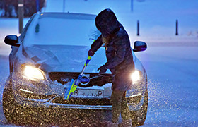 Personne qui enlève la neige sur sa voiture avec un balai à neige